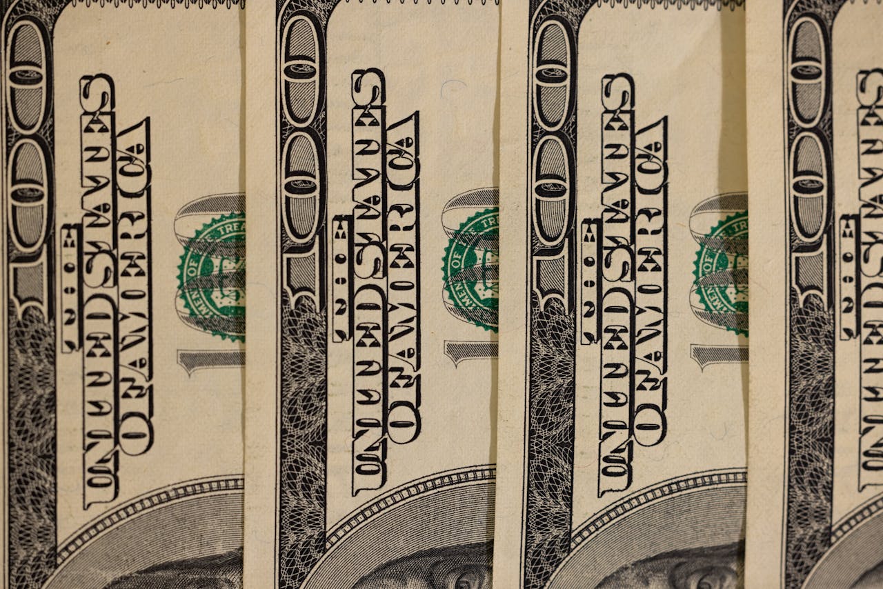 Detailed close-up of multiple US hundred dollar bills, showcasing currency design.